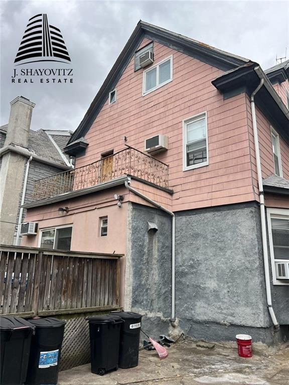 view of side of property with cooling unit, a balcony, and a wall unit AC