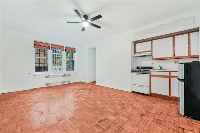 9430 Ridge Blvd Unit 1F, Brooklyn, NY 11209 - kitchen with radiator, white gas stove, freestanding refrigerator, under cabinet range hood, and white cabinets