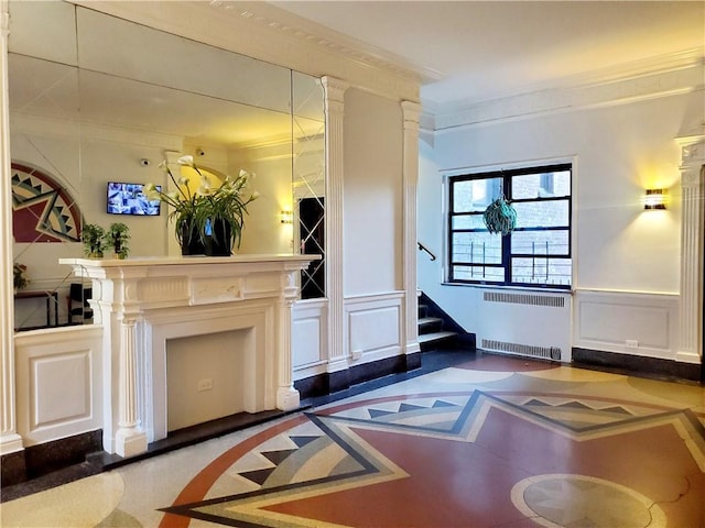 unfurnished living room featuring stairs, radiator, wainscoting, and ornamental molding