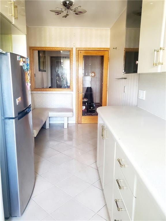 kitchen featuring stainless steel refrigerator, white cabinetry, ceiling fan, and light tile patterned floors