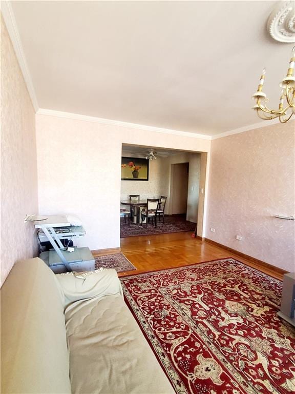 living room featuring hardwood / wood-style floors, crown molding, and a notable chandelier