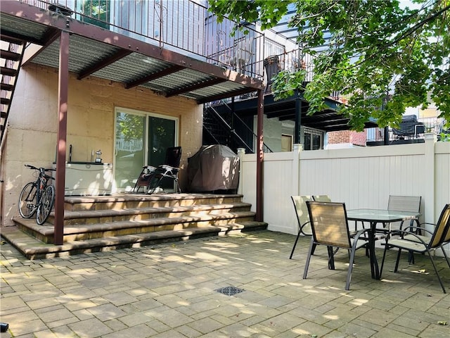 view of patio / terrace featuring stairs, fence, and outdoor dining area