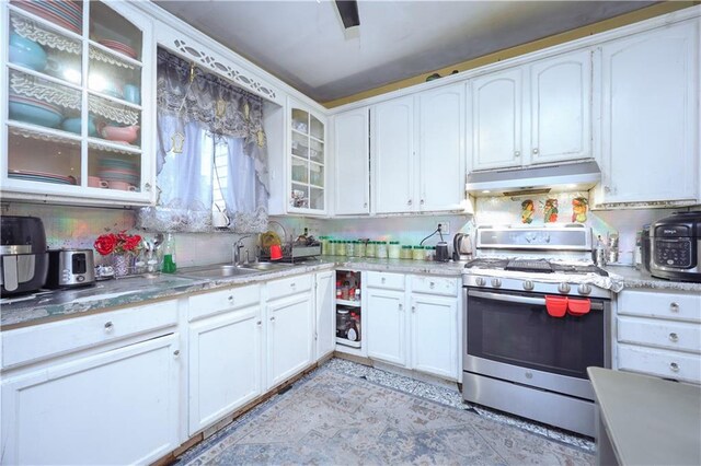 kitchen with white cabinets, gas range, sink, and backsplash