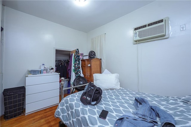 bedroom featuring hardwood / wood-style flooring and a wall unit AC