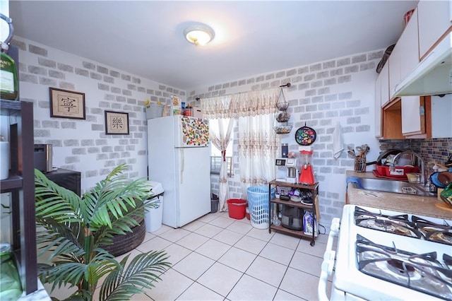 kitchen with brick wall, sink, white cabinets, and white appliances