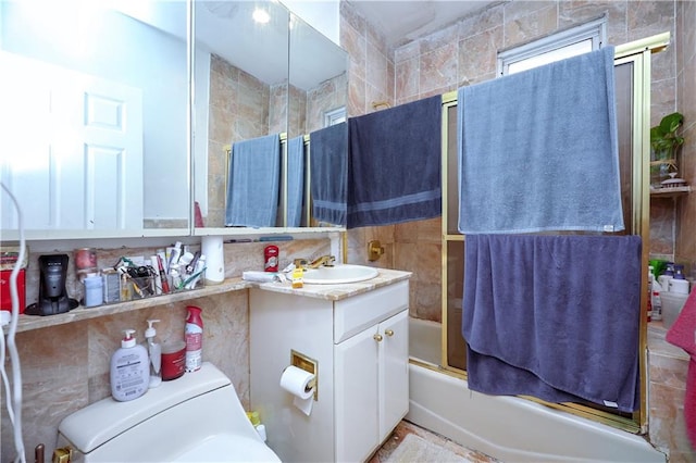 full bathroom with tile walls, vanity, enclosed tub / shower combo, and toilet