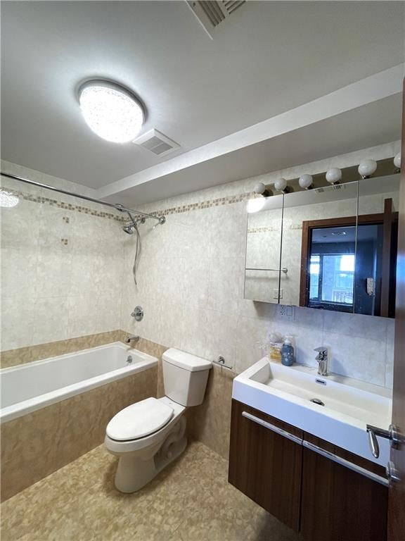 full bathroom with tiled shower / bath, vanity, tile patterned flooring, and toilet