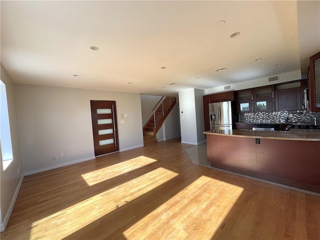 kitchen with dark brown cabinets, light hardwood / wood-style flooring, tasteful backsplash, and stainless steel fridge with ice dispenser