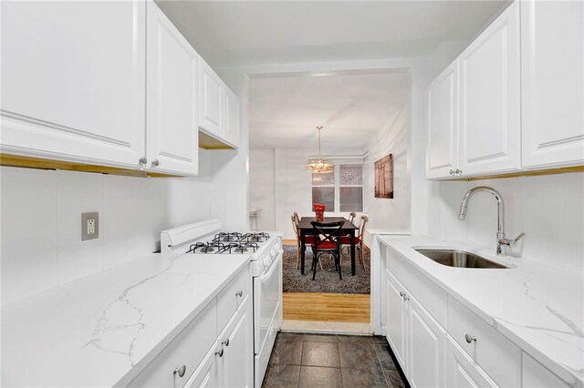9411 Shore Rd Unit 1A, Brooklyn, NY 11209 - kitchen featuring white gas stove, a sink, white cabinets, a chandelier, and light stone countertops