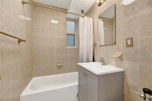 bathroom with shower / tub combo, vanity, and tile walls