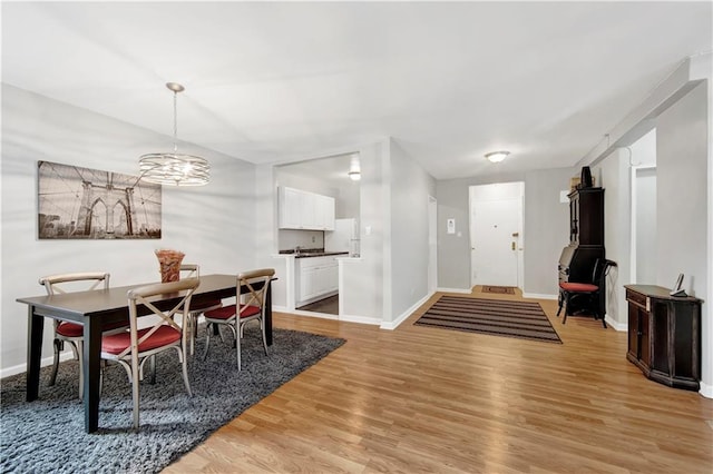 dining area featuring a chandelier, light wood-style flooring, and baseboards