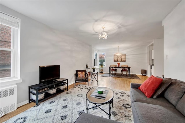 9411 Shore Rd Unit 1A, Brooklyn, NY 11209 - living area with radiator heating unit, a chandelier, wood finished floors, and baseboards