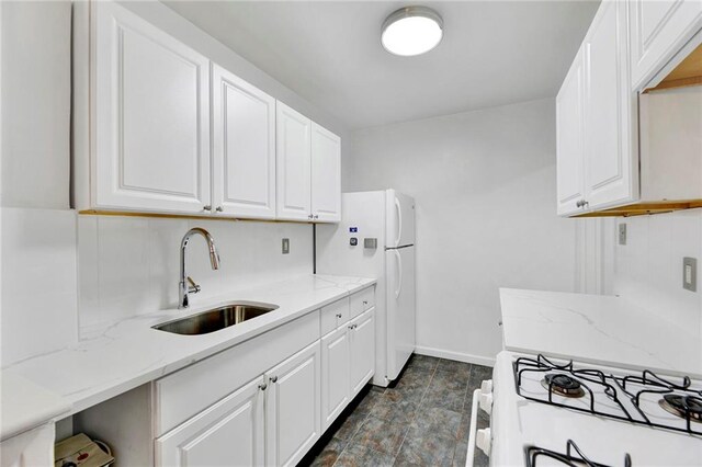 kitchen with light stone counters, sink, and white cabinets