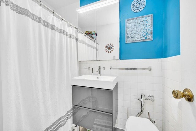 bathroom with vanity, tile walls, and toilet