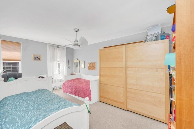 bedroom with ceiling fan, carpet floors, and a closet