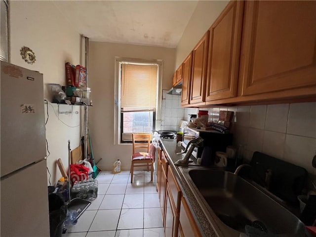 kitchen with sink, white refrigerator, backsplash, and light tile patterned flooring