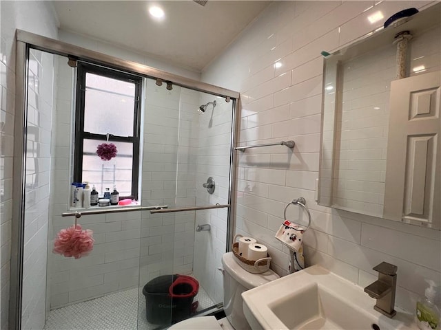bathroom featuring a sink, tile walls, a shower stall, and toilet
