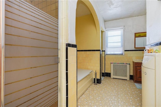 bathroom featuring tile walls, tile patterned flooring, and radiator heating unit