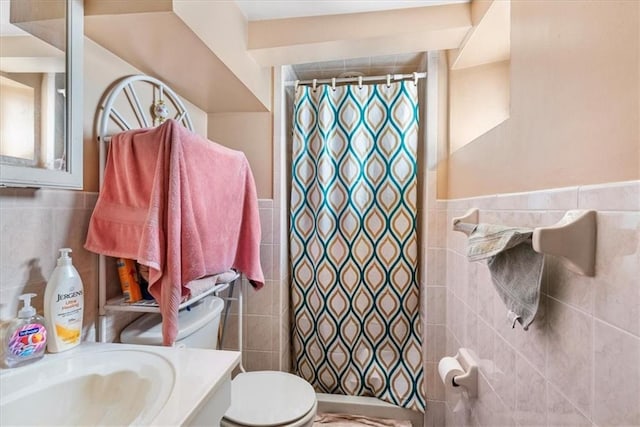 bathroom with walk in shower, tile walls, vanity, and toilet