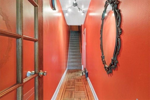 stairway with parquet floors and track lighting