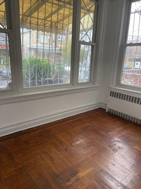 unfurnished dining area with dark parquet flooring and radiator heating unit