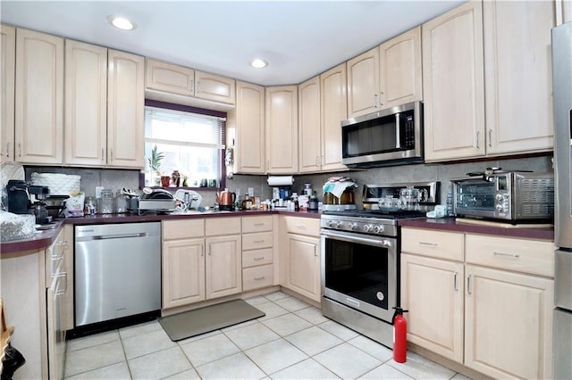 kitchen with light tile patterned flooring, stainless steel appliances, and backsplash