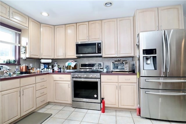 kitchen featuring stainless steel appliances, backsplash, and light tile patterned floors