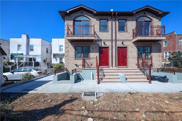 view of front of home with brick siding and a balcony