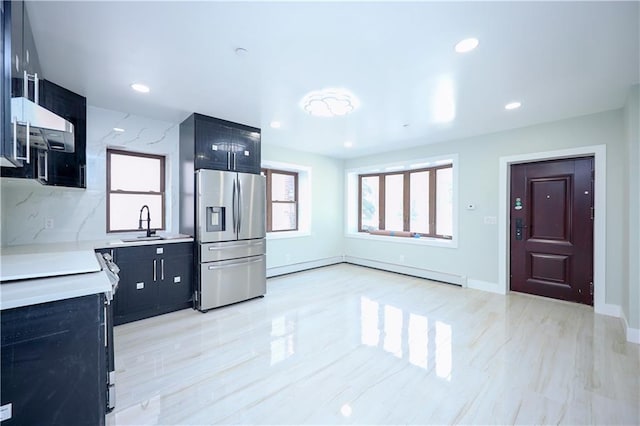 kitchen featuring dark cabinets, light countertops, stainless steel refrigerator with ice dispenser, and a sink