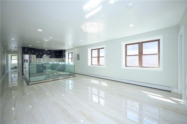 empty room featuring a baseboard heating unit, a healthy amount of sunlight, and electric panel