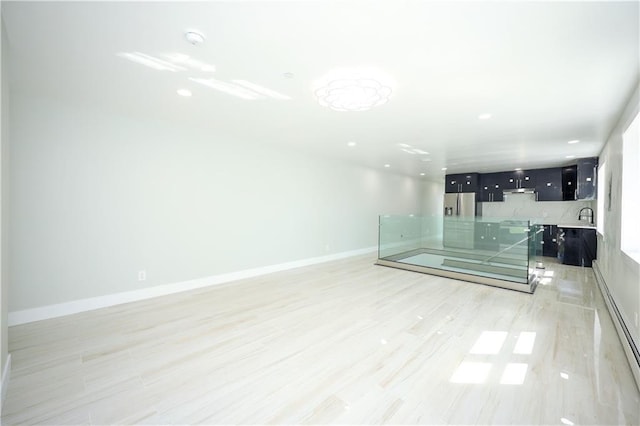 unfurnished room with a sink, baseboards, light wood-style flooring, and recessed lighting