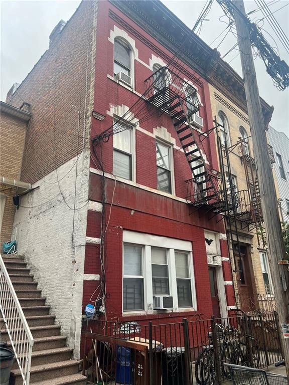 view of side of property featuring stairway, brick siding, and cooling unit