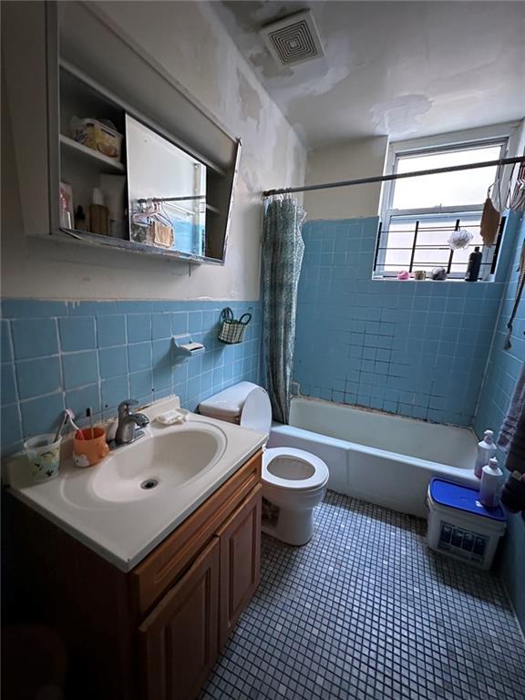 full bathroom featuring vanity, toilet, tile walls, and shower / bath combo