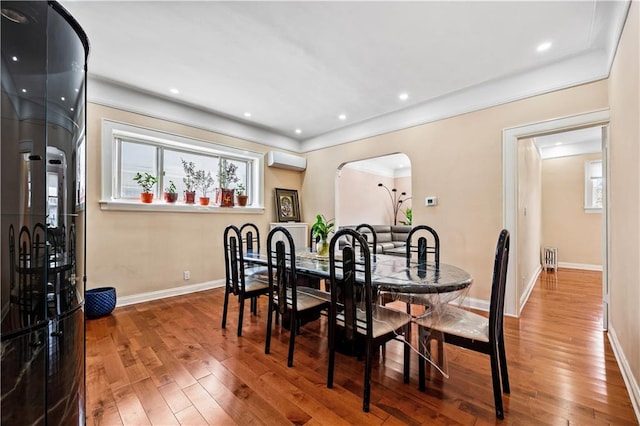 dining area featuring an AC wall unit and hardwood / wood-style floors