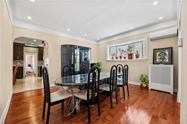 dining area with hardwood / wood-style floors and a wall unit AC