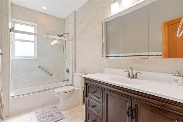 bathroom featuring tile walls, recessed lighting, toilet, enclosed tub / shower combo, and vanity