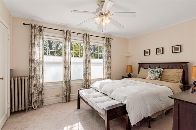 bedroom featuring radiator heating unit, a ceiling fan, and light colored carpet