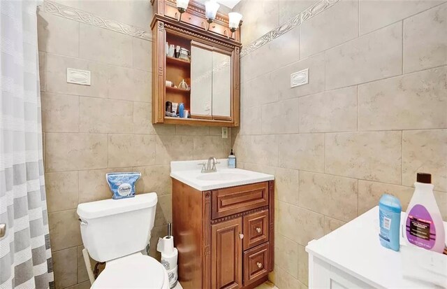 bathroom with vanity, tile walls, and toilet