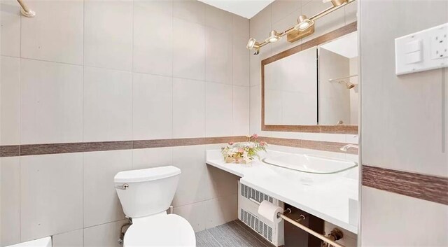 bathroom featuring vanity, toilet, tile walls, and radiator