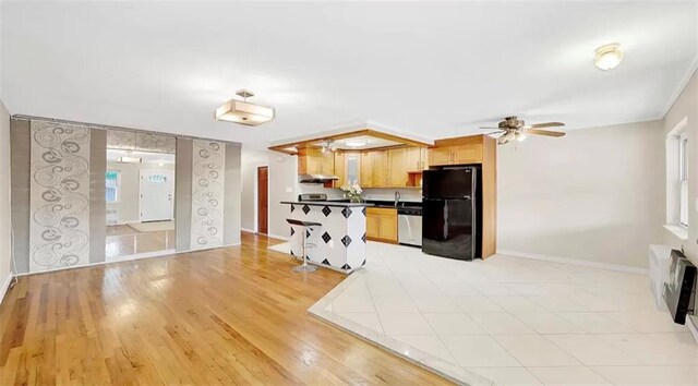 kitchen featuring black refrigerator, sink, stainless steel dishwasher, ceiling fan, and light hardwood / wood-style floors