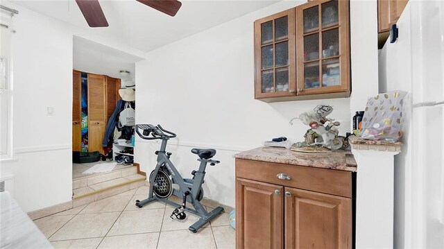 workout area featuring light tile patterned floors and ceiling fan