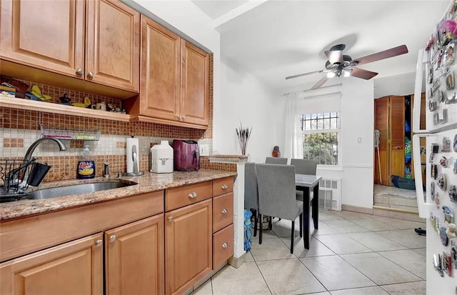 kitchen with decorative backsplash, light tile patterned flooring, light stone countertops, and sink