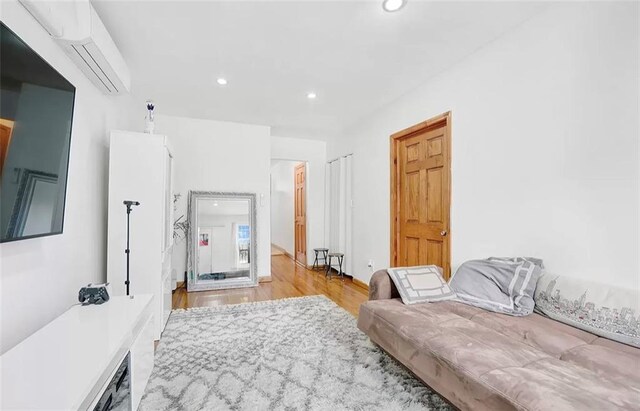 living room featuring an AC wall unit and light hardwood / wood-style flooring