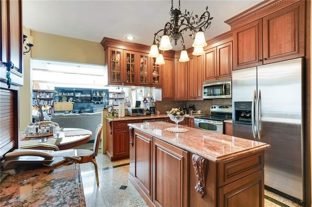 kitchen featuring a center island, stainless steel appliances, light stone counters, backsplash, and decorative light fixtures