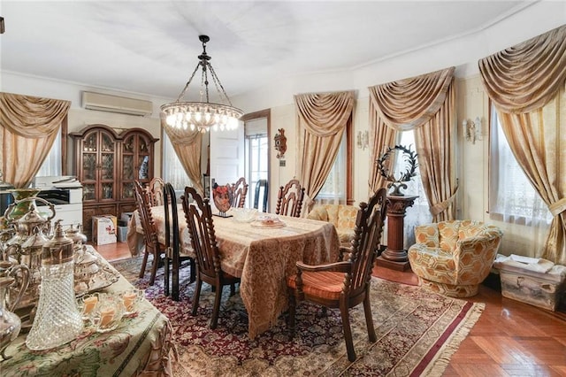 dining space featuring dark parquet flooring, an AC wall unit, and a notable chandelier