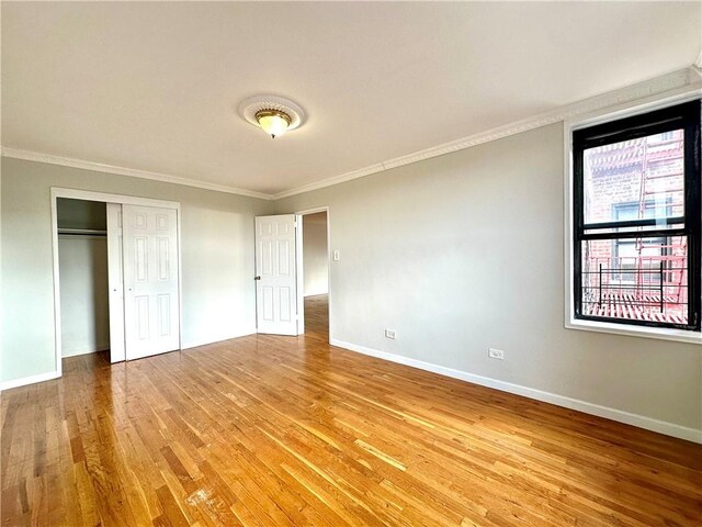 unfurnished bedroom with hardwood / wood-style flooring, ornamental molding, and a closet