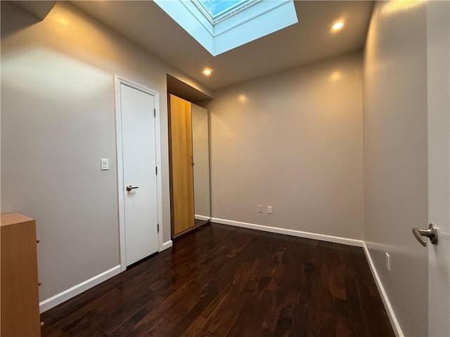 interior space featuring dark wood-type flooring and vaulted ceiling with skylight