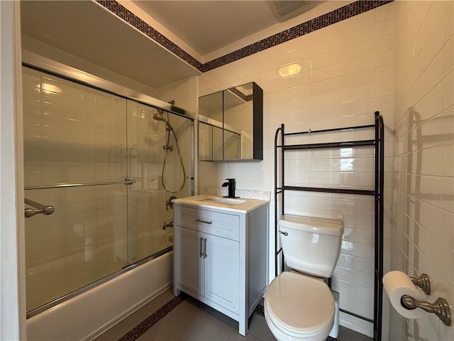 full bathroom featuring tile patterned flooring, vanity, tile walls, and shower / bath combination with glass door