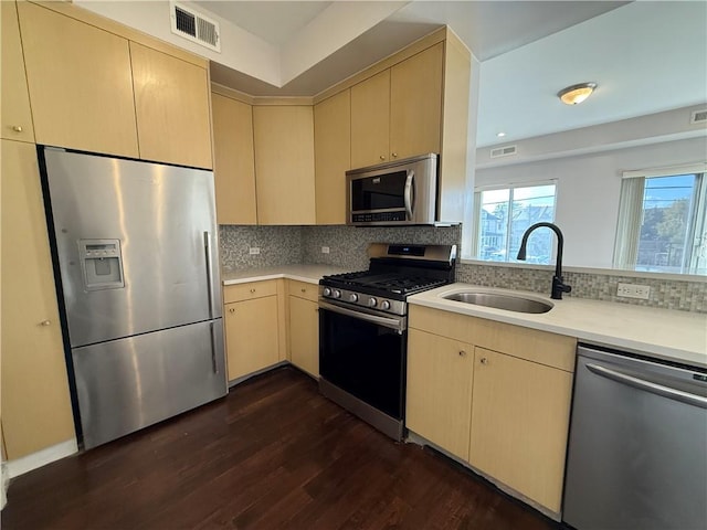 kitchen featuring appliances with stainless steel finishes, light brown cabinetry, tasteful backsplash, sink, and dark hardwood / wood-style flooring