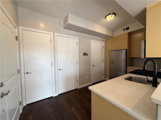 kitchen featuring dark hardwood / wood-style flooring, sink, stainless steel fridge, and light brown cabinetry